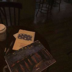 a table with some papers and a cup on it next to a coffee mug in a dark room