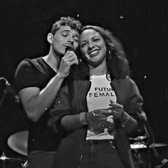 a man and woman sitting next to each other in front of a drum set with microphones