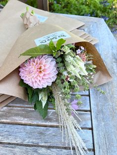 a bouquet of flowers sitting on top of a wooden table next to brown envelopes