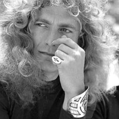 an old photo of a man with long curly hair and tattoos on his arm, looking off to the side