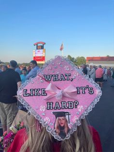 a woman wearing a pink graduation cap that says what like it's hard?