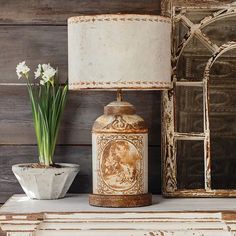 a vase with flowers sitting on top of a table next to a lamp