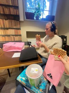 two people sitting at a table eating waffles and drinking coffee in front of bookshelves