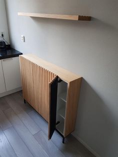 a kitchen with white cabinets and wood flooring next to a wall mounted microwave oven