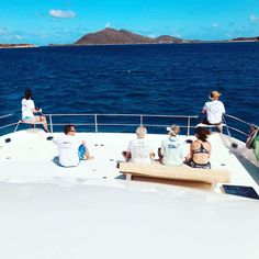 four people sitting on a bench looking out at the ocean from a boat in the water