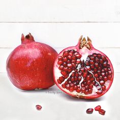 two pomegranates sitting next to each other on a white table top