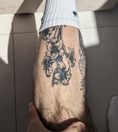 a man's arm with flowers on it and a white shirt underneath his leg