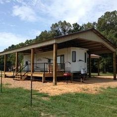 a mobile home sits in the middle of a grassy area with a fence around it