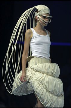 a woman is walking down the runway wearing a white dress and headpiece with long hair