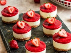 strawberry cheesecakes are arranged on a tray with fresh strawberries in the background