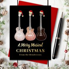 a christmas card with three guitars on it next to a fountain pen and pine cones