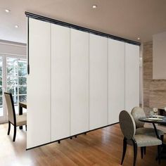 a dining room with white sliding doors and wooden flooring next to a large window