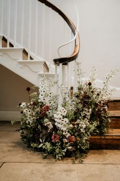 flowers and greenery on the ground in front of a stair case