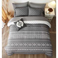 a bed with grey and white bedspread, pillows and pillow cases on it