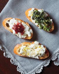 three pieces of bread with different types of food on them sitting on a table cloth