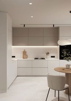 a modern kitchen with white cabinets and an island table in the center is lit by recessed lights