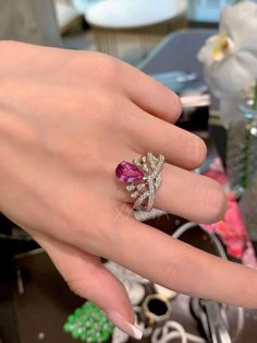 a woman's hand wearing a ring with two different colored stones on the middle