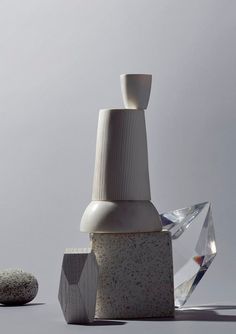 two white vases sitting next to each other on top of a table with rocks