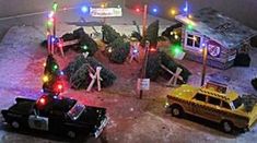 an assortment of toy cars and christmas lights in front of a small building with trees