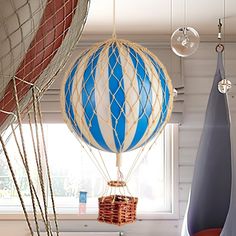 two hot air balloons in the shape of boats are suspended from hooks and ropes by strings