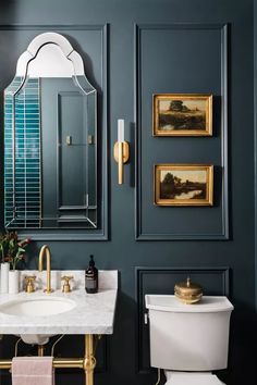 a bathroom with blue walls and gold accents, including a white toilet and sink in front of a mirror