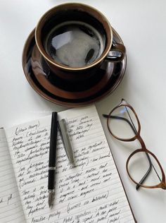 a cup of coffee next to a pen and glasses