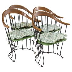 set of four chairs with green cushions on them