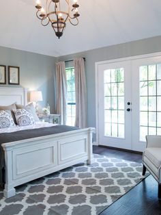 a bedroom with gray walls, white furniture and a chandelier hanging from the ceiling