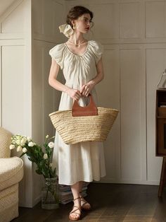 a woman in a white dress holding a wicker basket