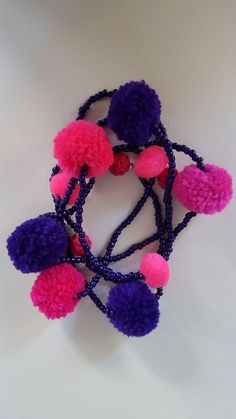 several different colored pom - poms are arranged on a white surface with black string