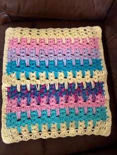 a crocheted blanket sitting on top of a brown couch