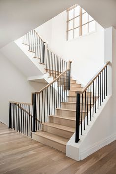 a stair case with black railing and wooden handrails in an empty room next to a window