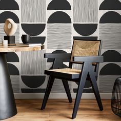 two chairs and a table in front of a wall with black circles painted on it