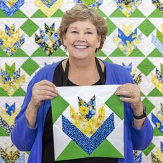 a woman holding up a piece of art that has been made into an origami