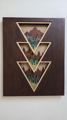 a wooden wall hanging with trees and mountains on it