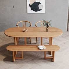 a wooden table with two chairs and a bench in front of a painting on the wall