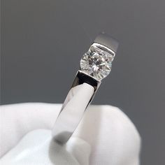 a close up of a person's hand holding a ring with a diamond in it