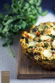 some food is sitting on a wooden cutting board next to greens and a knife,