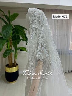 the back of a wedding veil with flowers on it, in front of a potted plant