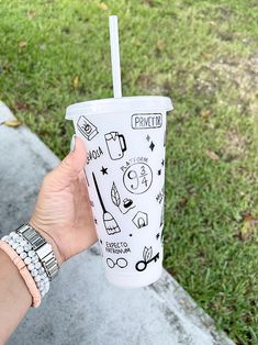 a person holding up a cup with some stickers on it and a straw in their hand