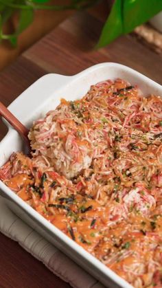 a casserole dish with meat and vegetables in it sitting on a wooden table