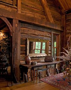 an old log cabin with wooden tables and chairs in front of a mirror on the wall