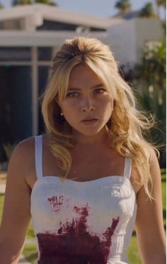 a blonde woman in a white top and red paint splattered on her body