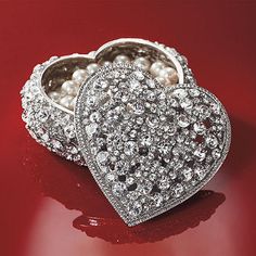 a heart shaped box with pearls inside on a red surface