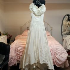 a wedding dress hanging on a bed in a room