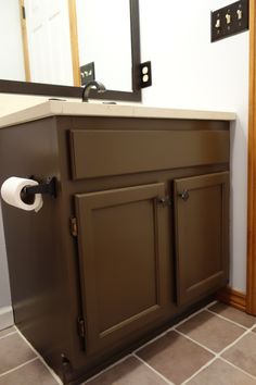 a bathroom with a sink, mirror and toilet paper dispenser