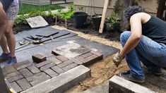 two people are working on some bricks in the yard