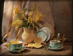 a vase filled with yellow flowers next to two cups and saucers