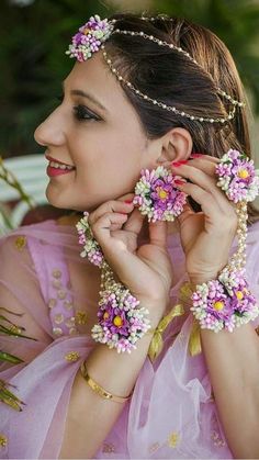 a woman in a pink dress is holding flowers on her head and wearing bracelets