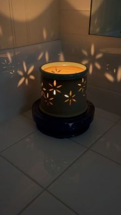 a lit candle sitting on top of a white tiled floor next to a mirror and wall